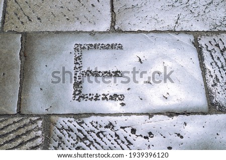 The letter E is engraved in stone close up