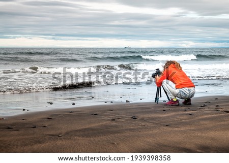 Landscape view of woman photographer tripod in Grundarfjordur beach in west Iceland with water waves on shore on Snaefellsnes peninsula