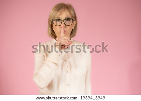 Senior lady showing silence gesture. Woman holding finger on lips. Can you keep a secret.