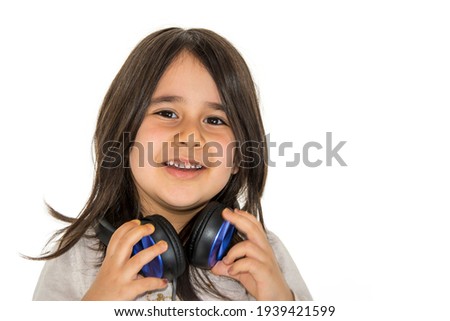 Little girl looking towards the camera and smiling while holding the headset