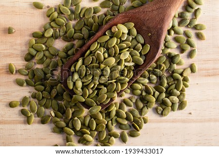 Roasted pumpkin seeds in a wooden spoon on wooden background