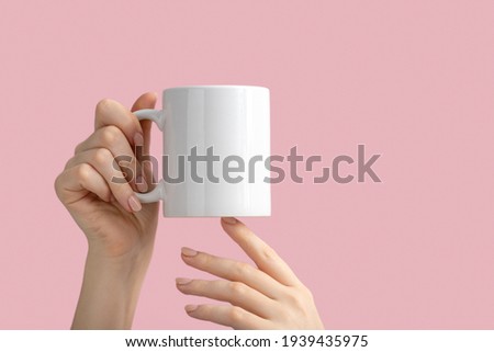 mockup white coffe cup or mug in female hands on pink background with copy space. Blank template for your design, branding, business. Real photo. Royalty-Free Stock Photo #1939435975