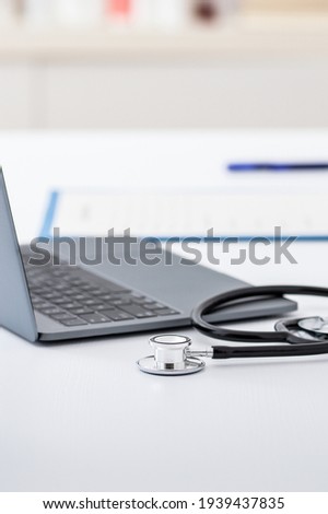 Closeup shot of a laptop, stethoscope and doctor's notebook on a table at hospital