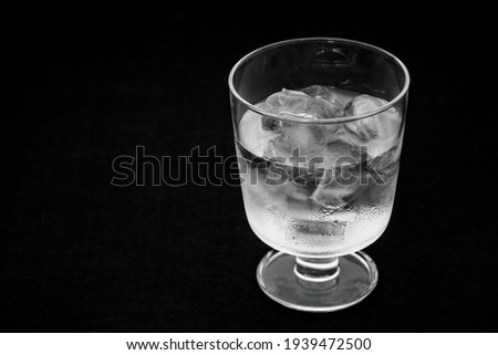 Close-up half-full glass with ice on black background