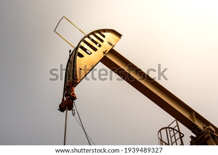Close-up at Beam pump or Donkey pump, operating for crude oil enhancing in petroleum production with clearly sky environment. Oil industrial operation and equipment object.