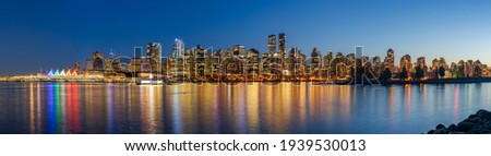 Night view of Vancouver downtown skyline panorama after sunset. Colorful buildings lights reflections on waterfront harbor. British Columbia, Canada.