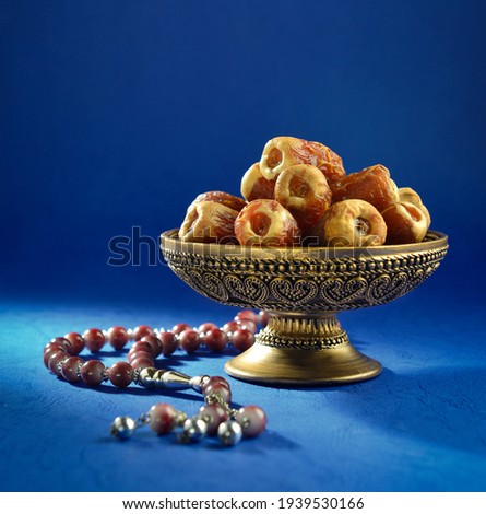 An ornamental bowl of dates with islamic prayer beads. 'Ramadan Kareem' stock photo of dates. Royalty-Free Stock Photo #1939530166