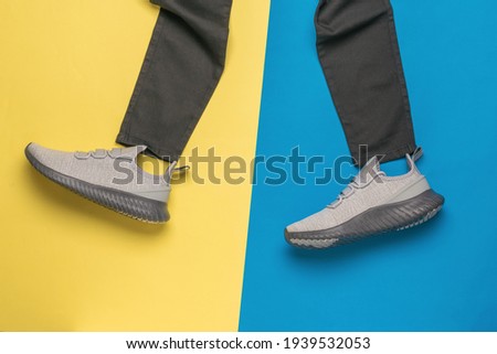Black pants and gray sneakers on a blue and yellow background. Fashionable youth casual clothing.