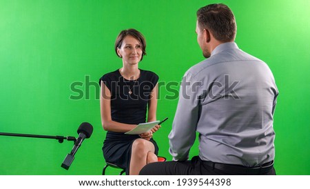 Young female presenter interviewing in television studio with green screen
