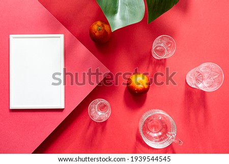 Mock up poster white photo frame top view.  Bright summer still life scene. Glasses of water and oranges fruits flat lay on red background