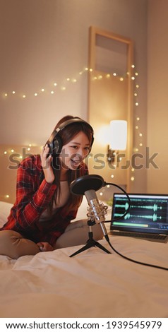 asian woman with microphone is recording podcast in bedroom at home