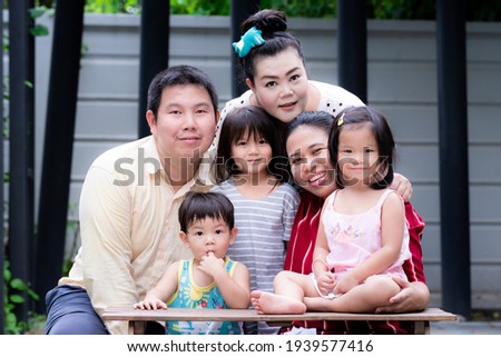 Happy family concept. Boy and girls and adults in the family take pictures together. Children suck their fingers. Sweet smile. Everyone looking at the camera.
