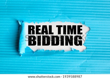 Real Time Bidding RTB. text on white paper over torn paper background.