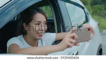 Woman use cellphone to take photo and sit inside car