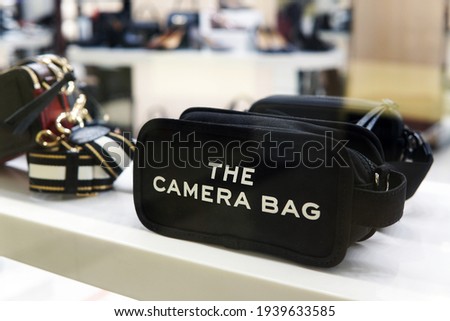 A handy black camera bag is displayed in the window of a fashion store. Fashionable and convenient accessory for everyday use.