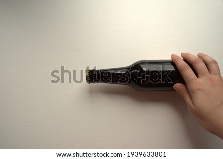 Picture of a female hand holding a beer bottle with a view from above