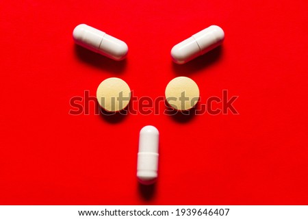 Angry face made by pills , antibiotics and probiotics, medical red background