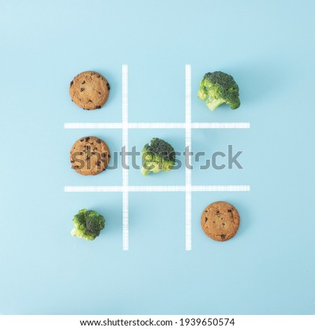 In this board game 
broccoli beats chocolate chip cookies, that means healthy food is better than junk food, so win this game. Creative flat lay concept. Royalty-Free Stock Photo #1939650574