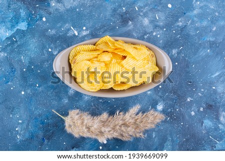 Reeds on blue, chips in bowl, unhealthy food, snacks. High quality photo