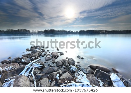Stones in the water on the Vistula river at sunrise, clouds in the sky, long exposure photography