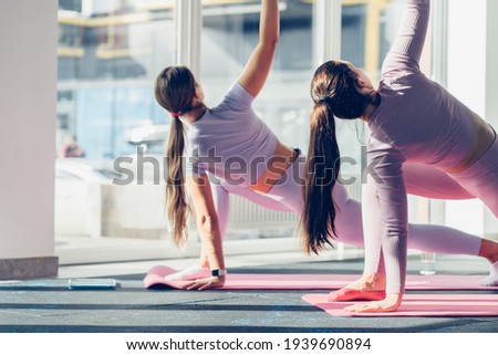 Back view of slim young women practice yoga in fitness studio. Wellness concept. Bright sun shine morning. Toned. Royalty-Free Stock Photo #1939690894