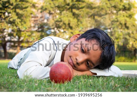 young boy lying on the ground looking into cricket ball
