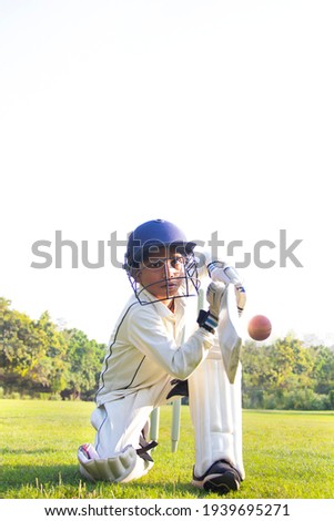 Young boy batting in protective gear during a cricket Royalty-Free Stock Photo #1939695271