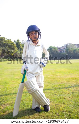 Boy in cricket uniform holding a cricket bat  Royalty-Free Stock Photo #1939695427