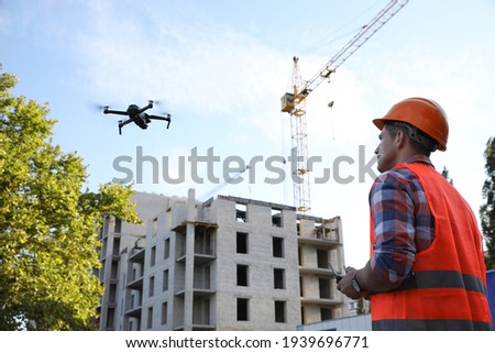 Builder operating drone with remote control at construction site. Aerial photography