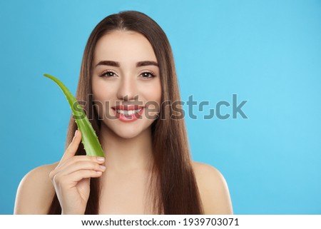 Young woman with aloe vera leaf on light blue background. Space for text