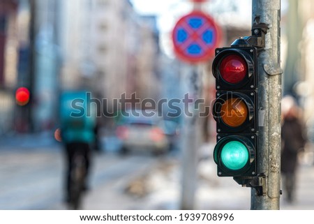 closeup of small traffic semaphore with green light against the backdrop of the city traffic