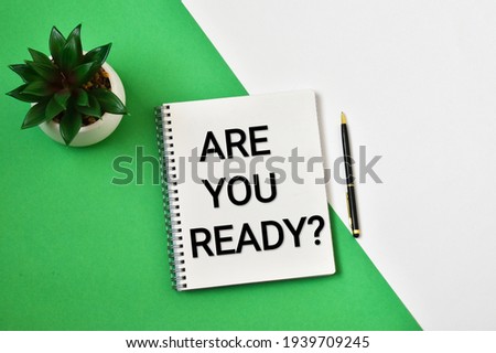 Green plant with text in a notepad ARE YOU READY on white-green background.