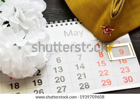 May 9. St.  Calendar, white flowers and a military cap on a wooden background. the traditional symbol of Victory Day 1945. Victory Day holiday. Postcard. copy space.