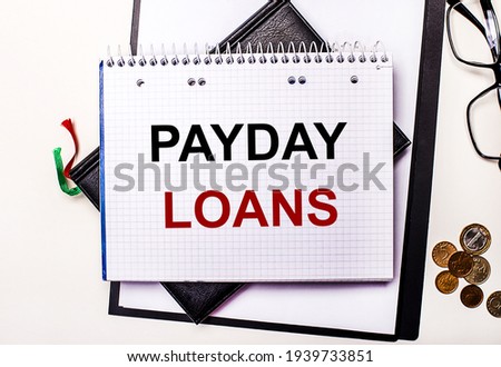 On a light background glasses, coins and a notebook with the inscription PAYDAY LOANS. Business concept