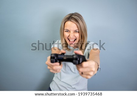 pretty young blond attractive woman posing on blue background with game controller in hand