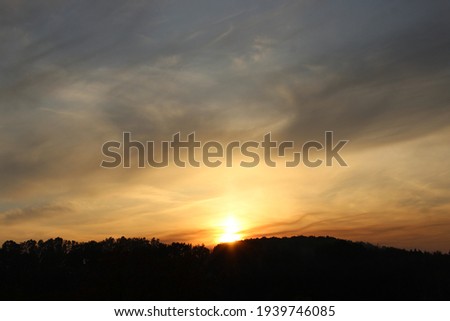 The photo shows an autumn sunset. The dark outlines of the trees merge abruptly into the autumn sky. In the sky you can see the non-native surf of the clouds.