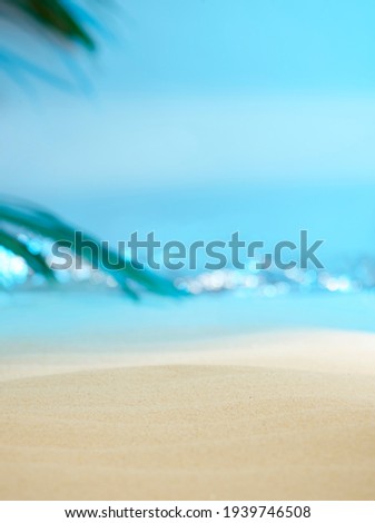 Soft focus, dreamy, sandy beach with palm tree leaf and sparkling waves