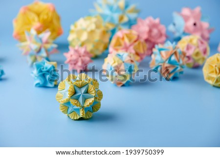 Set of multicolor handmade modular origami balls or Kusudama Isolated on blue background. Visual art, geometry, art of paper folding, paper crafts. Close up, selective focus, copy space.
