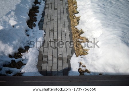 Melting snow around a patio tiled path, springtime shot