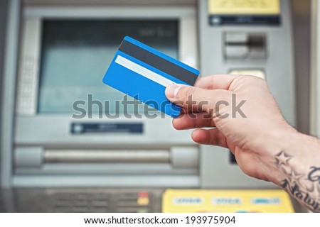 Hand holding plastic card near ATM. Bank card payment.