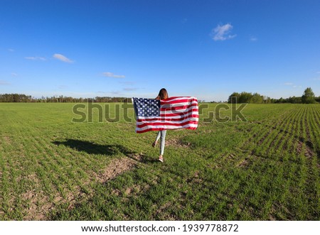 Happy beautiful girl with American flag. America's Day. A young woman in nature with an American flag. Patriotism and love. 4th of July. Freedom. Independence Day. Space for text