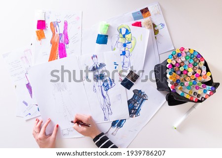 young brunette woman designing fashion dresses and drawing with colored pencils  various colorful fashion drawings
