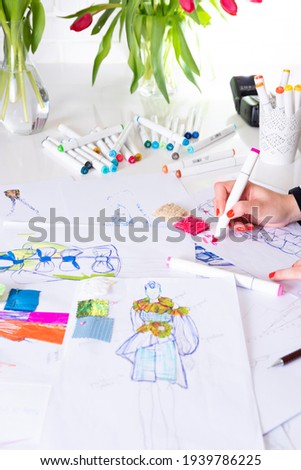 young brunette woman designing fashion dresses and drawing with colored pencils  various colorful fashion drawings