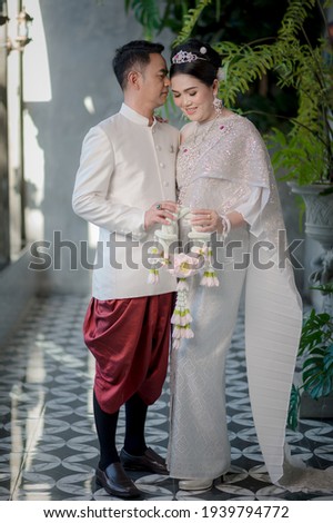 Asian couples happily take pre-wedding pictures with Thai suit and pink dress before getting married.