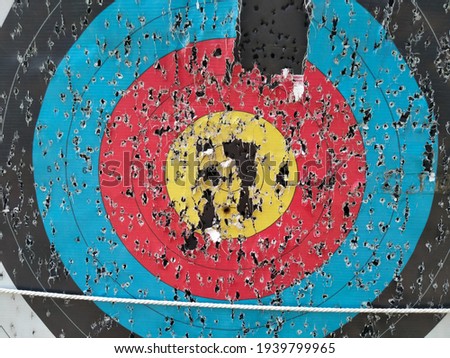Archery target close up with many arrow holes in Gold, red, blue and black  Royalty-Free Stock Photo #1939799965