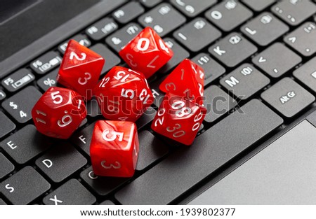 Set of simple red RPG role playing fantasy board game dice laying on a modern laptop computer keyboard, closeup, from above, nobody. Online rpg pc games, roleplay, nerd culture abstract concept