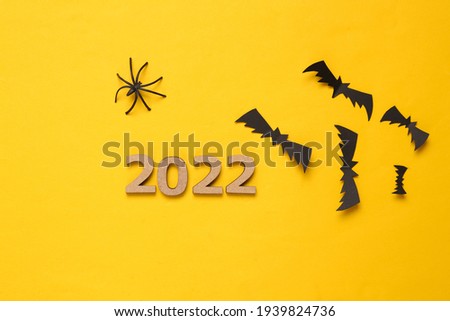 Halloween 2022. Bats, spiders and 2022 on yellow background