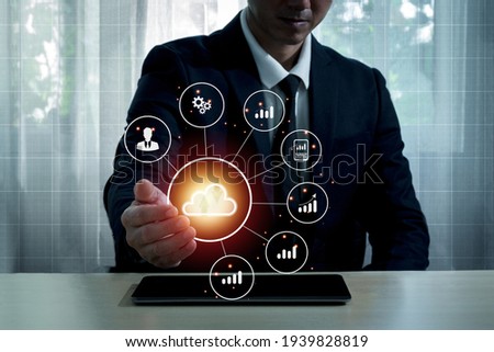 A man in a suit uses his right hand to hold the cloud computing symbol in his hand and the business symbol is placed around it.