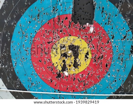 Archery target close up with many arrow holes in Gold, red, blue and black  Royalty-Free Stock Photo #1939829419