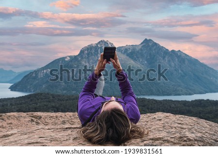 woman checking mobile, relaxed in mountainous forest
